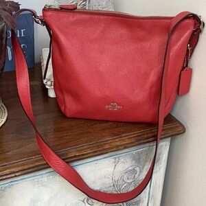 Coach red pebbles dufflette bag with adjustable buckle straps.